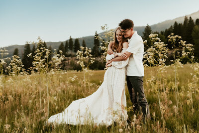 A husband wraps his arms around his wife who is wearing a flowing white dress at Crystal Peak Verdi.