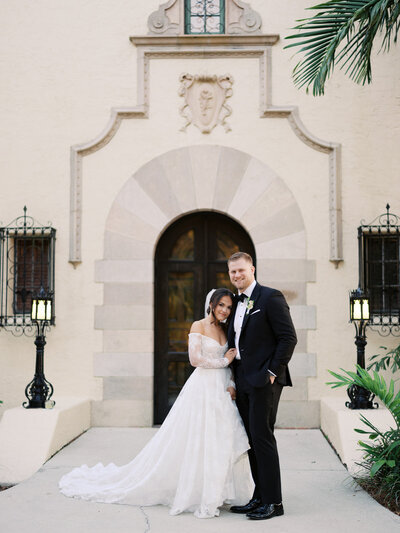 Bride and groom stand in front of The Powel Crosley Estate in Sarasota, Florida—capturing timeless elegance at a historic waterfront wedding venue, planned by Watters & Co. Events