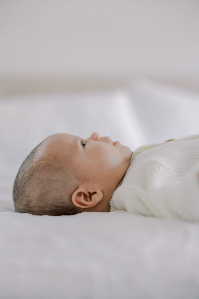 A baby looks up at his mother during his newborn photography session.