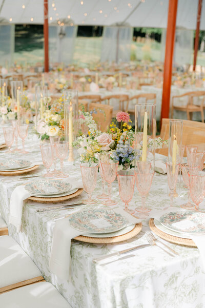 soft pink crystal glasses with floral pattern linens and plates, and yellow blue and pink florals arrangements designed by Sirpilla Soirees, Wedding Planners in Columbus Ohio