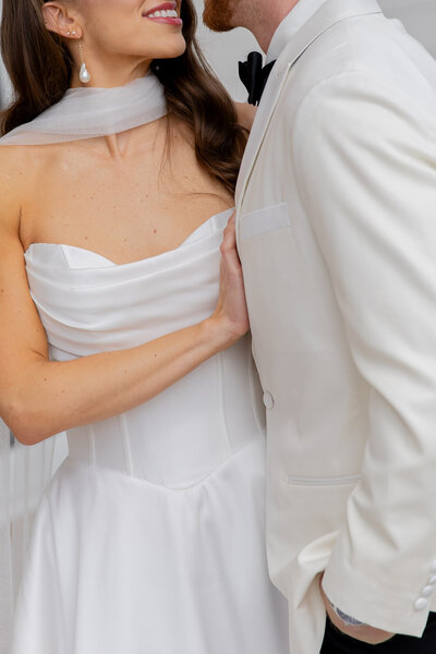 A close up, cropped shot of a bride and groom on their wedding day. They're turned in towards each other and smiling.