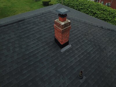 Close-up of completed roof with brick chimney, installed by Black Bear Roofing.