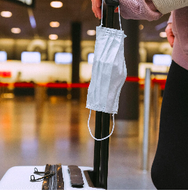 Traveler holding a face mask at an airport, highlighting essential health tips for safe and stress-free travel.
