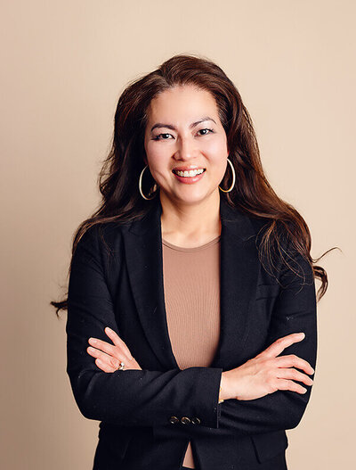 Woman folds arms and looks at camera during her headshot session.
