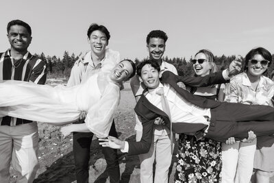 Friends hold the bride and groom during group photos after their wedding ceremony in the Puget Sound.