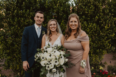 A newlywed couple posing for a photo with a bridesmaid.