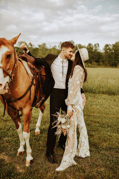 Bride and groom with horse in rustic field setting