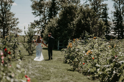couple walking on a green path surrounded by flowers