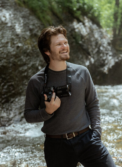 A photographer posing at a mountain lake 