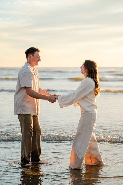 Engagement session at Pismo Beach during golden hour, with warm light glowing over the ocean.