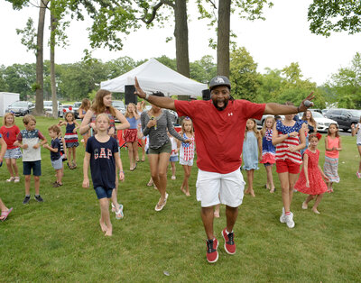 DJ dancing with kids on grassy lawn
