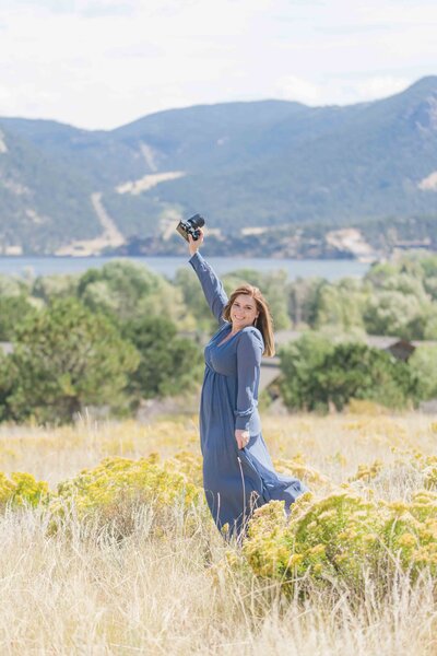 female photographer posing in a field with camera