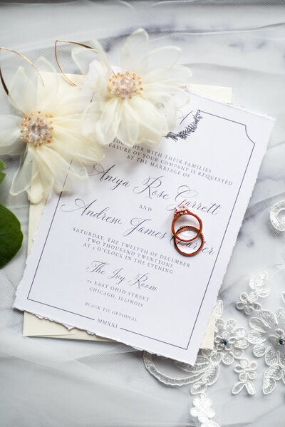 Two gold wedding rings on an invitation suite.