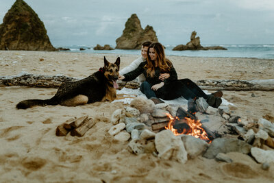 B & T smiling looking at their s'mores cooking over the campfire on the beach