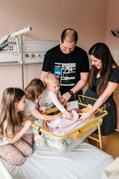 Tatínek a starší sourozenci v porodnici s novým sourozencem