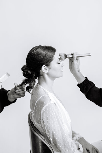Black and white photo of bride getting hair and makeup done