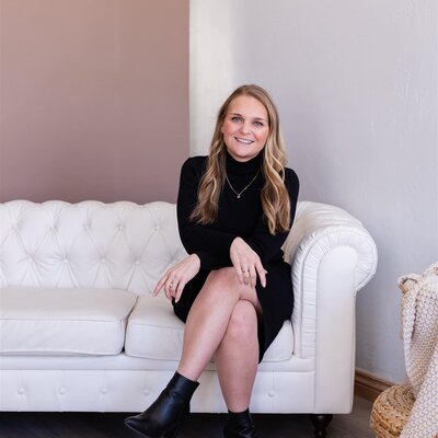 Jessica wearing a white blazer, smiling as she writes in her planner