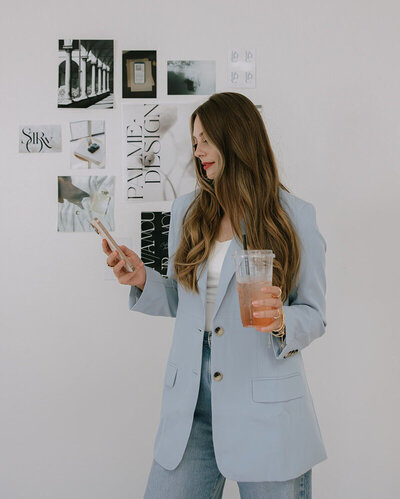 showit branding and website designer​ Palme Design Co on her phone holding a soda