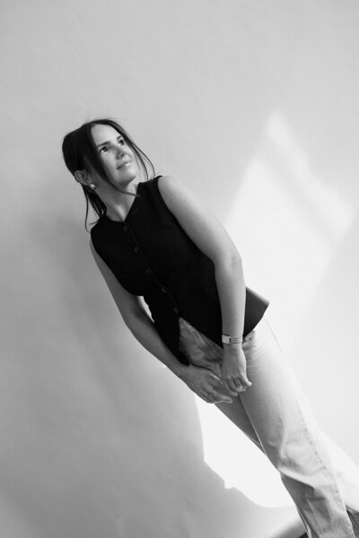 Alexandra Eveland in a yellow t-shirt and blue jeans sitting in a chair and smiling softly