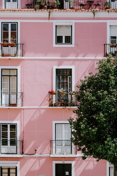 a pink exterior of a building with windoes and small balconies covered in different decorations