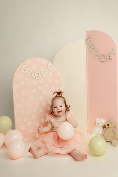 Minimalist digital illustration of a baby girl in a pink tutu and crown, seated on a soft blush background to celebrate a one-year milestone captured by duehr photography in minneapolis