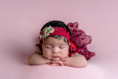 Newborn in red outfit posing during her studio newborn session in Stamford, CT.