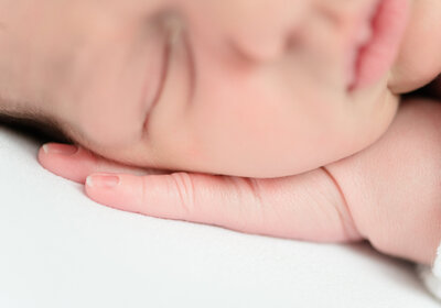 Baby fingers resting under a head.