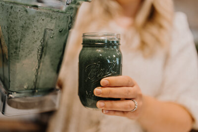 Kenna pouring a postpartum smoothie into a mason jar