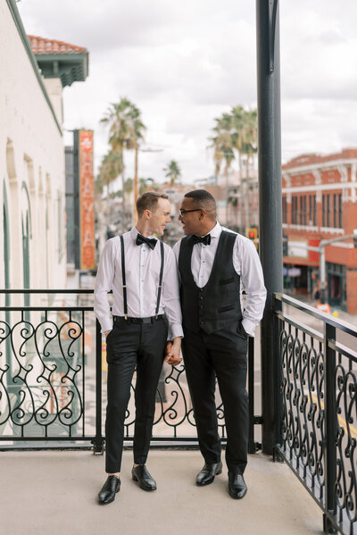 LGBTQIA Groom and Groom smiling at each other on the balcony at Hotel Haya in Ybor City Tampa Florida