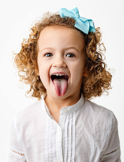 A girl sticks her tongue out during her Personality Session in the studio at Angela Marie Media.