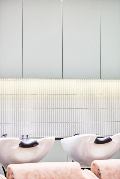Minimalist salon design featuring sleek white basins and textured wall panels, highlighting a chic Sydney hairdresser space.