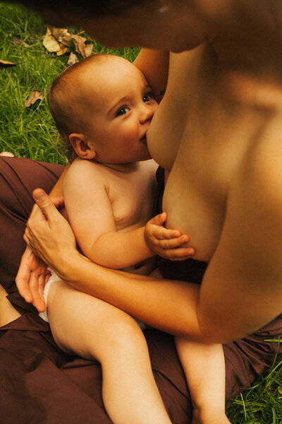 A portrait of a baby being breast fed by her mother in an Auckland park. Captured by Eilish Burt Photography