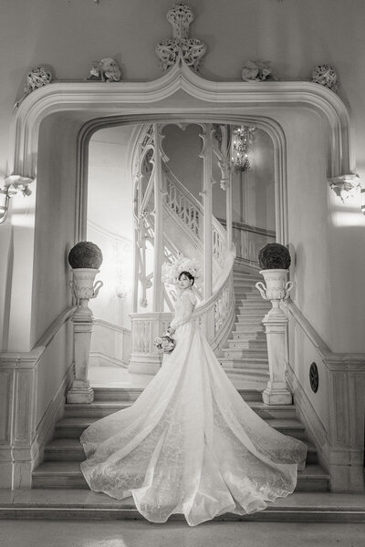 Bride on the grand staircase at Château Challain, captured in elegant, romantic wedding photography.
