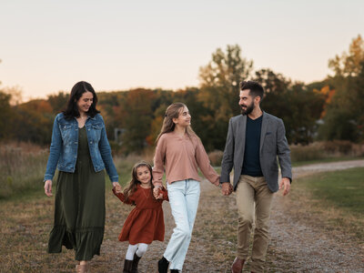 mom and dad walking with their one year old daughter for family photoshoot