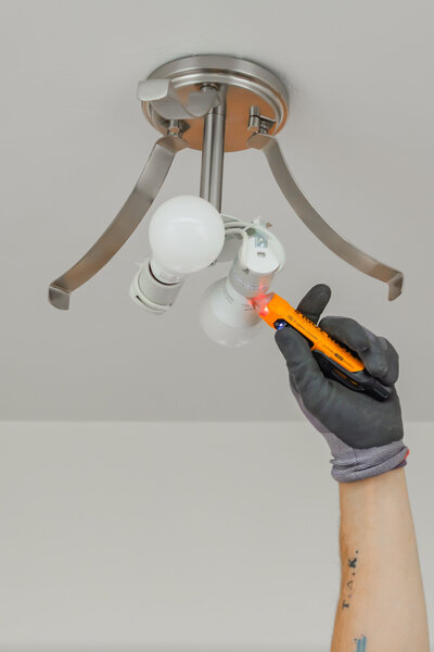 Electrician in Albuquerque installing light fixture in home