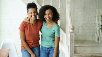 Two girls with arms around shoulders laughing