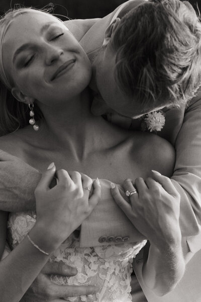 groom hugging bride from behind and kissing her neck