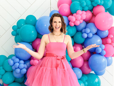 The creative and premier balloon artist in Raleigh. Dressed in a charming pink dress, our expert is behind a stunning blue and pink balloon installation.