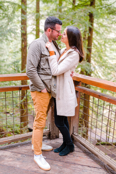 oregon engagement photography at the Hoyt Arboretum in Portland Oregon where couple is standing on the redwood deck, belly to belly and staring in each others eyes while sharing a sweet smile