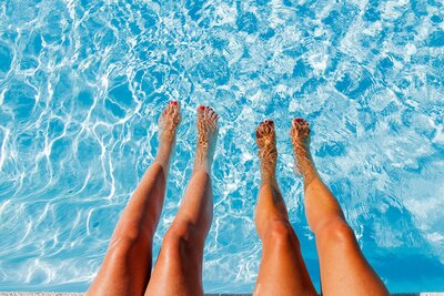 Overhead photo of two girls kicking their feet in an bright blue pool