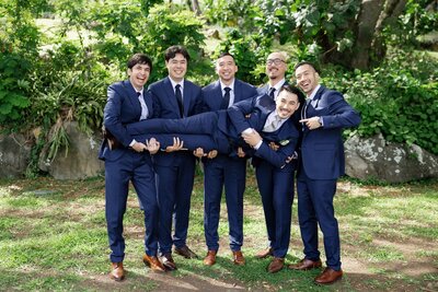 A wedding party holding up a newlywed across them 