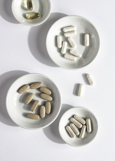 small white bowls of different health supplements against a white background