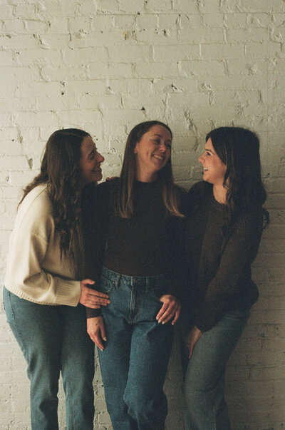  friends laughing together against wall 