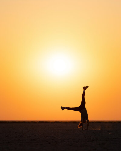 Person doing a cartwheel with an orange sunset in the background