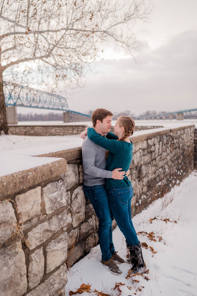 A couple is captured by the camera hugging another while standing in the winter snow.