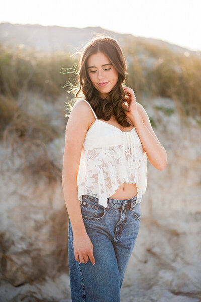 orlando high school senior picture of a girl in white top and jeans on the beach