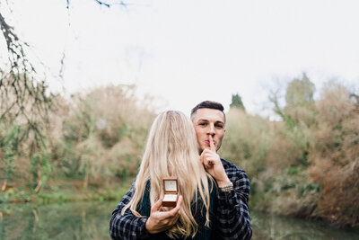A man and a woman hugging each other with the man secretly holding an engagement ring behind the womans back taken by Cornwall Wedding Photographer and Devon Wedding Photographer Liberty Pearl
