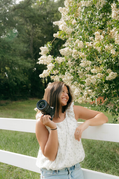 Esperanza Curl, Alabama-based photographer, smiling with camera in hand near blooming trees — founder of EC Photography