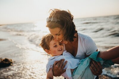 Mother on beach holding son and laughing