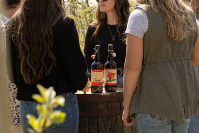 Friends enjoying hard cider tasting around barrel table at Applebottom Orchards.